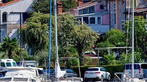 Un puerto deportivo con barcos amarrados, una iglesia con campanario y edificios residenciales al fondo.