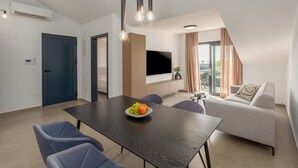 A modern living room with a dark wooden dining table, grey sofas, and a flat-screen TV mounted on the wall. - Luxury seaview apartment in Funtana (Funtana)