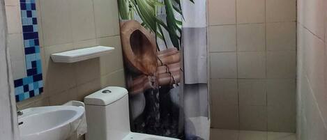 Un baño con inodoro, bidé, lavamanos y cortina de ducha con estampado de bambú.
