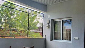 Una habitación con una mesa, sillas, un ventanal con persianas y una lámpara en el techo.