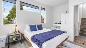 Un dormitorio moderno con una cama grande, una mesita de noche, un escritorio y un armario.