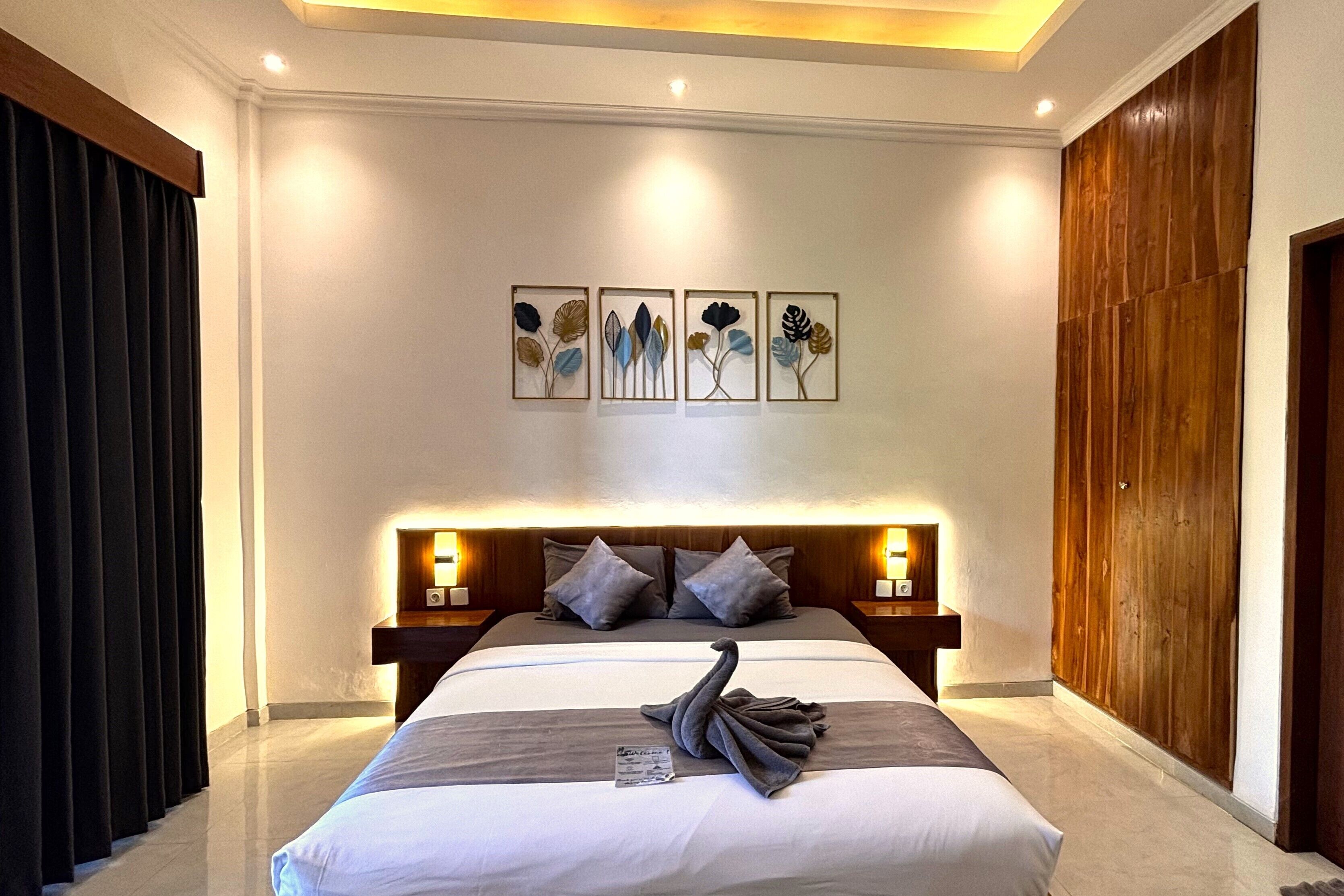 A hotel room with a large bed, wooden headboard, and wall-mounted artwork.