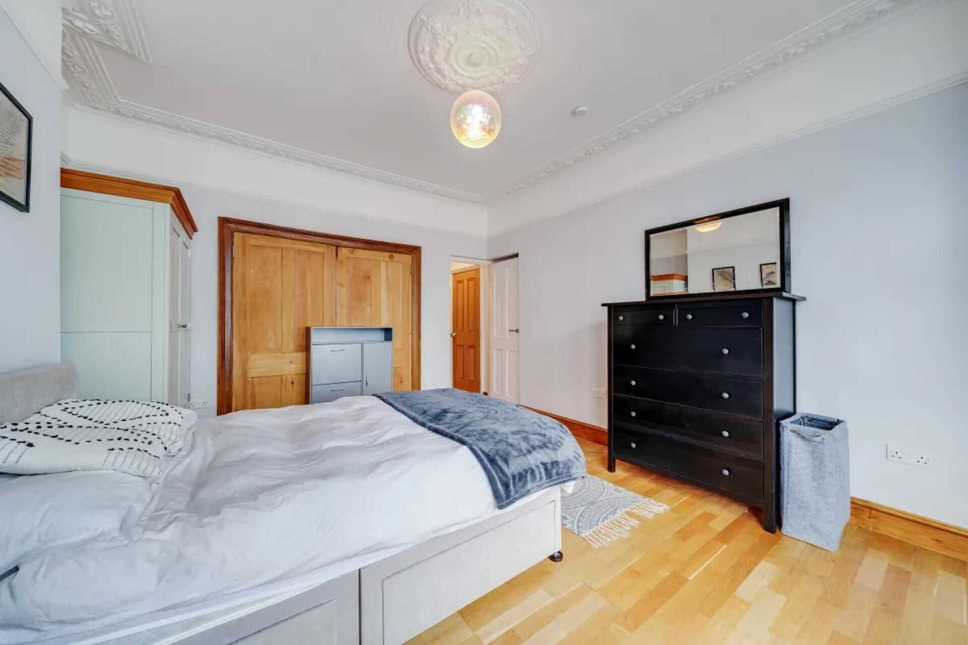 A bedroom with a bed, a dresser, a wardrobe, and a mirror.