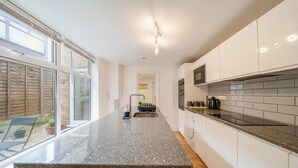 Eine moderne Küche mit Granit Arbeitsplatte, weißen Schränken und Blick auf den Garten durch große Fenster.