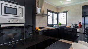 A modern kitchen with a built-in oven, microwave, and a large window providing natural light. - Luxury Villa with Stunning Ocean & Mountain View’s (Montaña Roja)