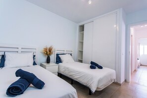 A hotel room with two beds, white bedding, a wardrobe, and a nightstand with a vase of dried flowers. - Luxury Villa with Stunning Ocean & Mountain View’s (Montaña Roja)