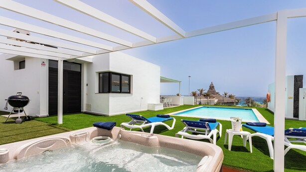 A modern outdoor pool area with a hot tub, lounge chairs, and a view of the ocean. - Luxury Villa with Stunning Ocean & Mountain View’s (Montaña Roja)
