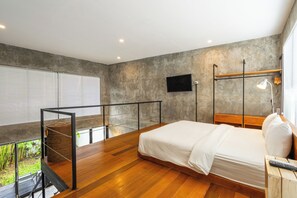 Une chambre moderne avec un grand lit, un téléviseur fixé au mur et un balcon offrant une vue sur la verdure.
