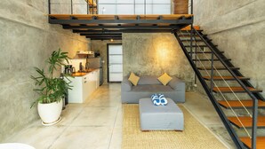 Un appartement moderne de style « loft », comprenant une cuisine, un espace de vie et un escalier menant à un niveau supérieur.