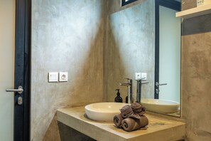 Une salle de bain avec un grand miroir, un lavabo et un porte-serviettes.