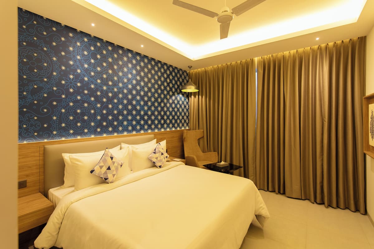 A hotel room with a large bed, a ceiling fan, a nightstand, and a wall with a star pattern.