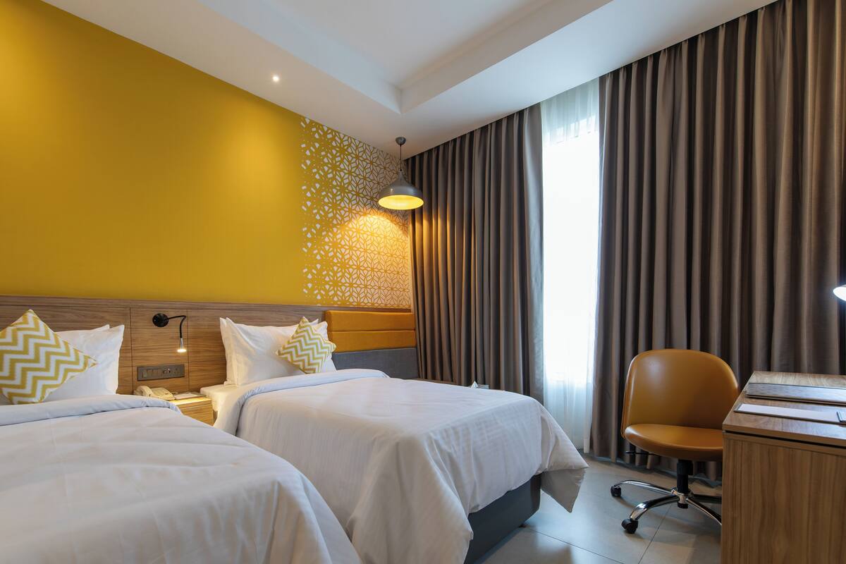 A hotel room with two beds, a desk, and a chair.
