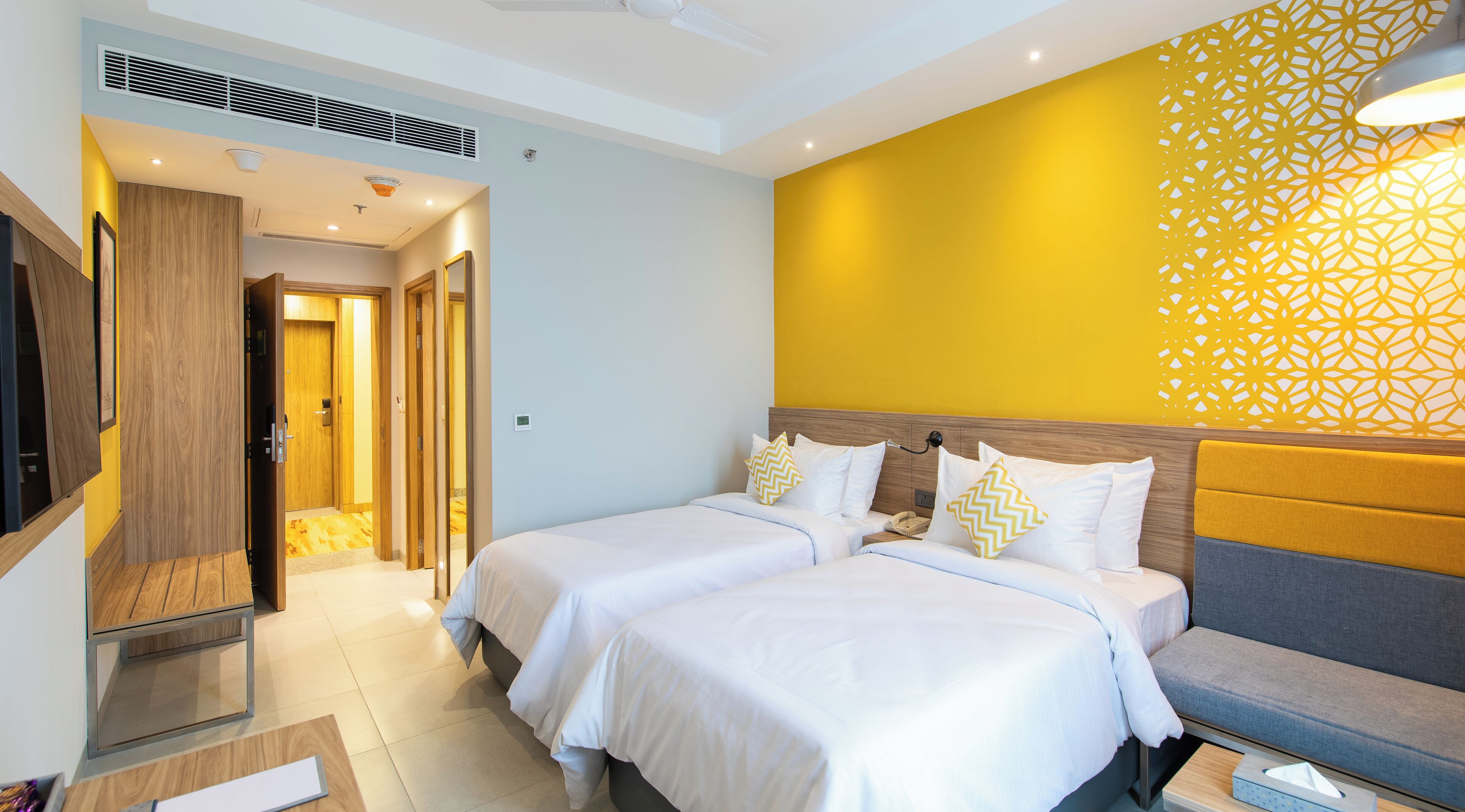 A hotel room with two beds, a TV, and a decorative wall.
