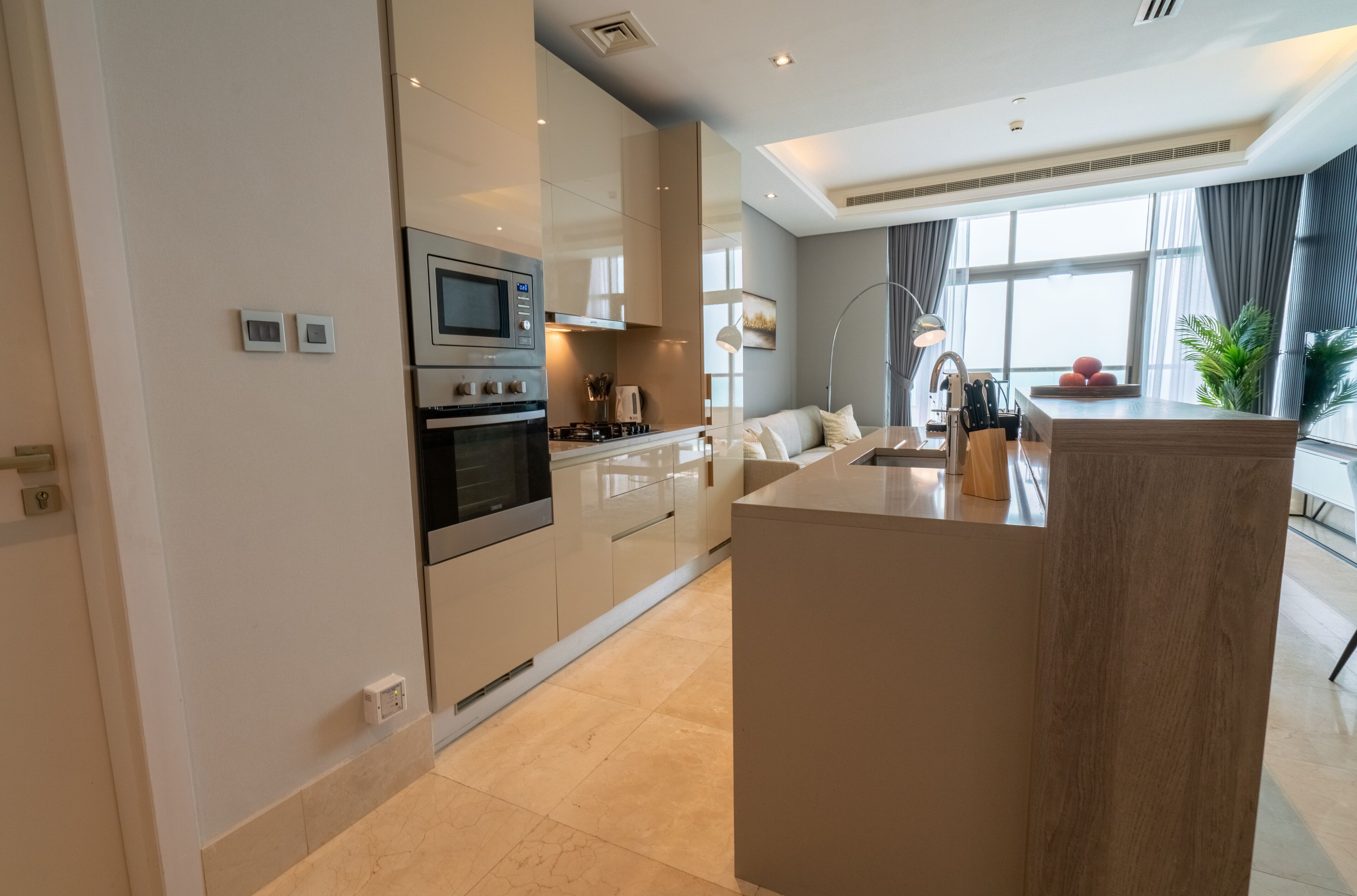 A modern kitchen with a central island, built-in appliances, and a large window providing natural light.