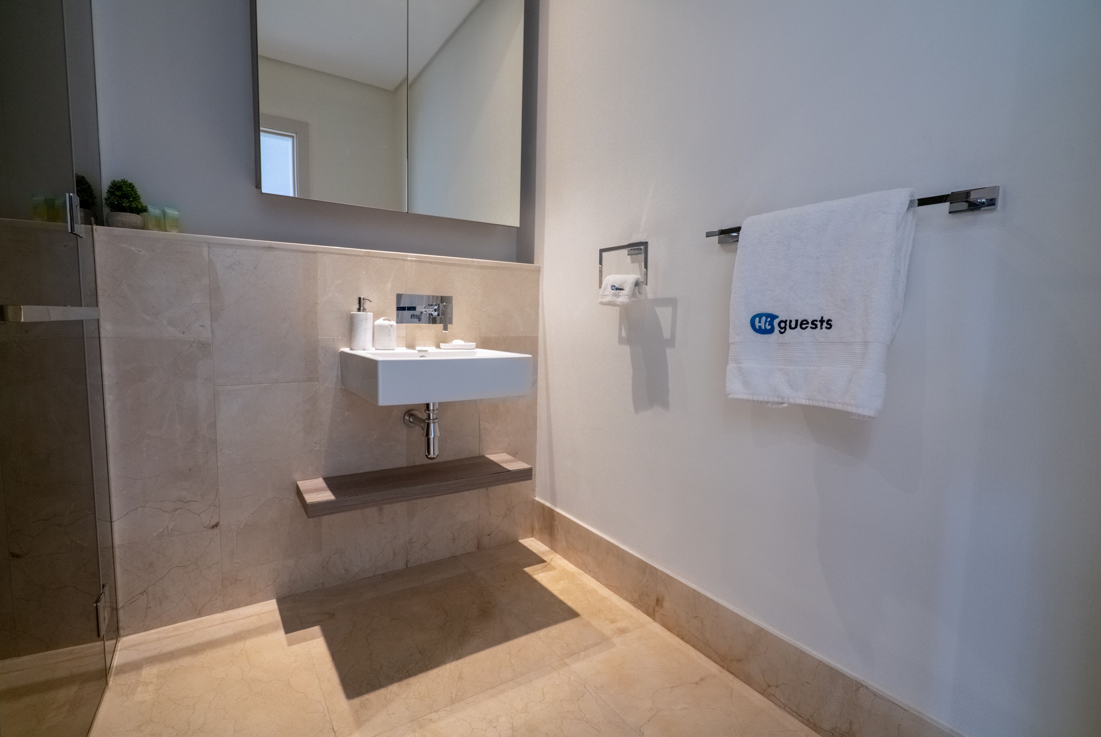 A modern bathroom with a marble sink, a towel rack with a towel, and a mirror above the sink.