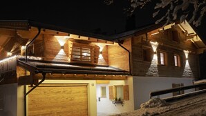 A wooden chalet with a sloped roof, a visible garage, and a snow-covered ground. - Bergchalet Four Seasons (Reit im Winkl)