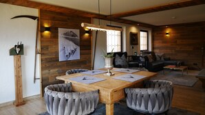 A cozy dining area with a wooden table, cushioned chairs, and a vase of flowers. - Bergchalet Four Seasons (Reit im Winkl)