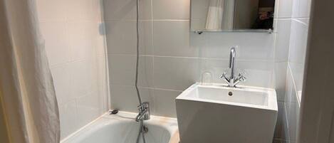 A bathroom with a bathtub, a sink, and a mirror.