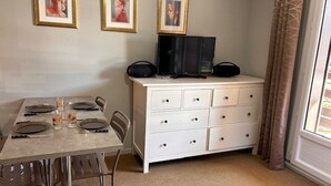 A dining area with a table set for four, a white dresser with drawers, and framed pictures on the wall. - Cozy Studio for 4 with Ski Lift Access and South-Facing Balcony (Risoul)