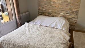 A bedroom with a bed, a window with curtains, and a stone-patterned wall. - Cozy Studio for 4 with Ski Lift Access and South-Facing Balcony (Risoul)