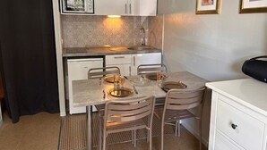 A compact kitchen with a dining table, chairs, a microwave, and a coffee maker. - Cozy Studio for 4 with Ski Lift Access and South-Facing Balcony (Risoul)