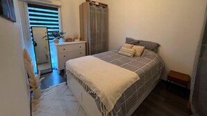 Een slaapkamer met een bed, nachtkastje en een kledingkast.