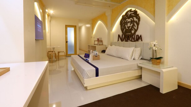 Una habitación de hotel moderna con una cama grande, un escritorio, una silla y una escultura decorativa de cabeza de león en la pared.