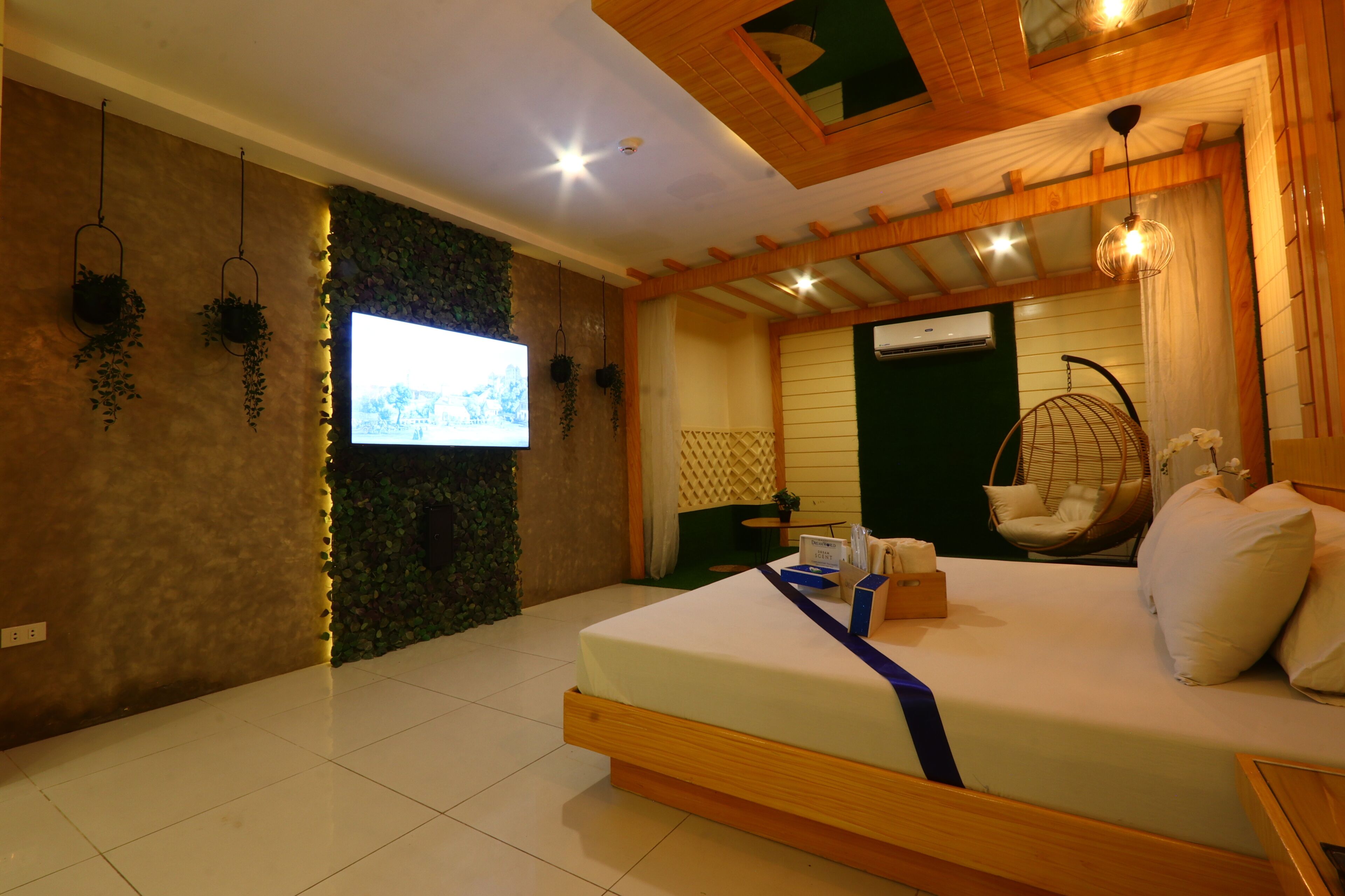 Un dormitorio moderno con cama, televisión, plantas colgantes y una silla colgante.