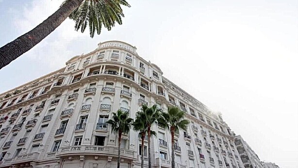 Un edificio de varios pisos con estilo arquitectónico clásico, que presenta balcones y una fachada curva.