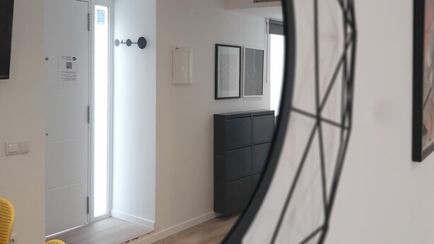 A hallway with a white door, a black cabinet, and two framed pictures on the wall.