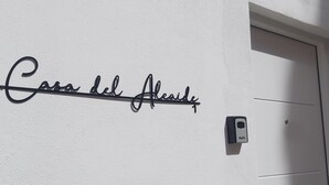 A wall with the text "Casa del Alcázar" and a door with a light switch and a sensor.