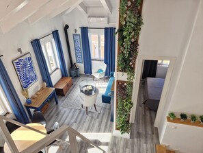 A spacious living area with a high ceiling, a wooden bench, a round coffee table, and a white sofa. - Beautiful duplex with private terrace, 2 bedrooms - Málaga Center (Málaga)