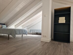A spacious attic bedroom with high ceilings, wooden flooring, and a built-in black shelving unit. - Beautiful duplex with private terrace, 2 bedrooms - Málaga Center (Málaga)