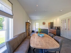 Enjoy meals at the central dining table surrounded by comfortable seating and a kitchen island.