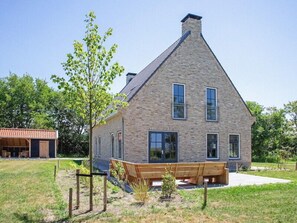 Stunning two-story house with a prominent chimney and multiple windows, some with balconies, set amidst a beautifully landscaped outdoor area.