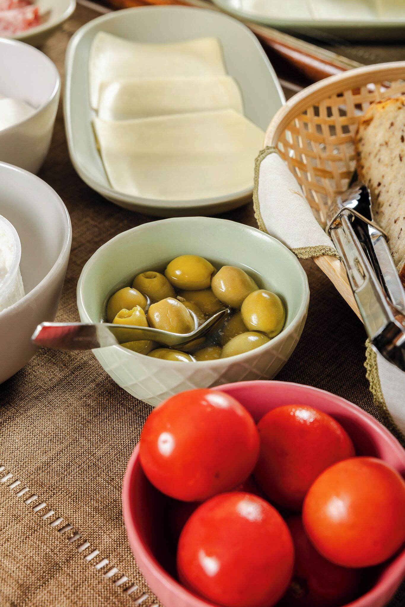 Una mesa con diversos alimentos, como aceitunas, tomates y queso.