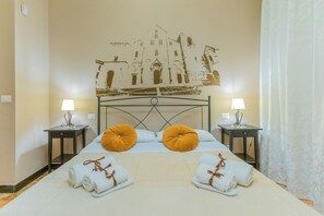 A hotel room with a bed, two bedside tables with lamps, a wall mural, and towels on the bed.