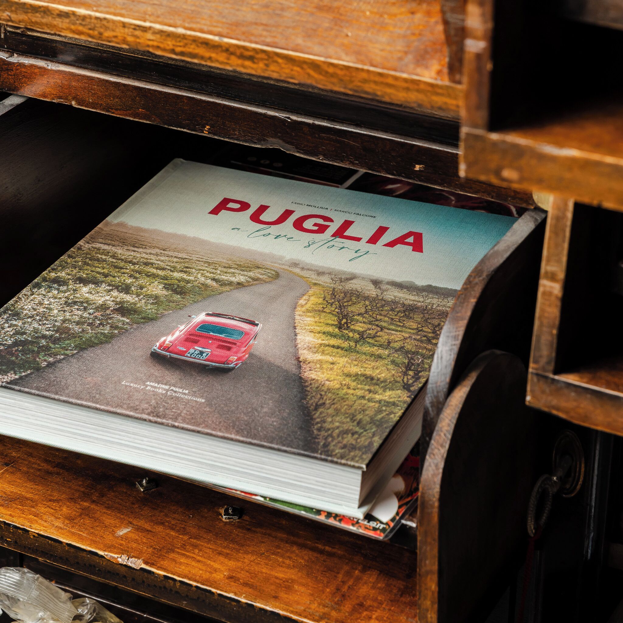 A magazine titled 'Puglia a love story' with a red car on a road.