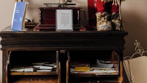 Un gramófono antiguo sobre un soporte de madera con un cartel, un osito de peluche y un árbol de Navidad.