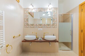 A bathroom with two sinks, a mirror, and a shower.