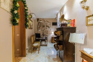 Un soggiorno con un pianoforte a legni, una televisione, una libreria e un orologio a parete.
