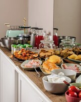 Un tavolo per buffet con diversi cibi, tra cui pizza, panini e assortimenti di salse.