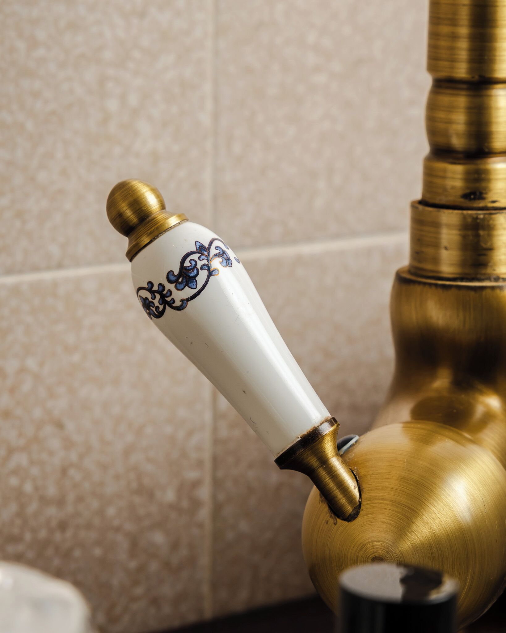 Een badkamer met een messing kraan en een witte keramieken knop met blauwe patronen.