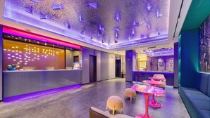 A modern hotel lobby with a reception desk, seating area, and a ceiling with unique lighting. - Xinghe Yuezhi·S Hotel (Guangzhou Yuexiu Park Railway Station Subway Station Baima Clothing City Flagship Store) (Guangzhou)