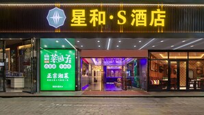 A hotel entrance with a neon sign, glass doors, and a visible interior with seating and tables. - Xinghe Yuezhi·S Hotel (Guangzhou Yuexiu Park Railway Station Subway Station Baima Clothing City Flagship Store) (Guangzhou)