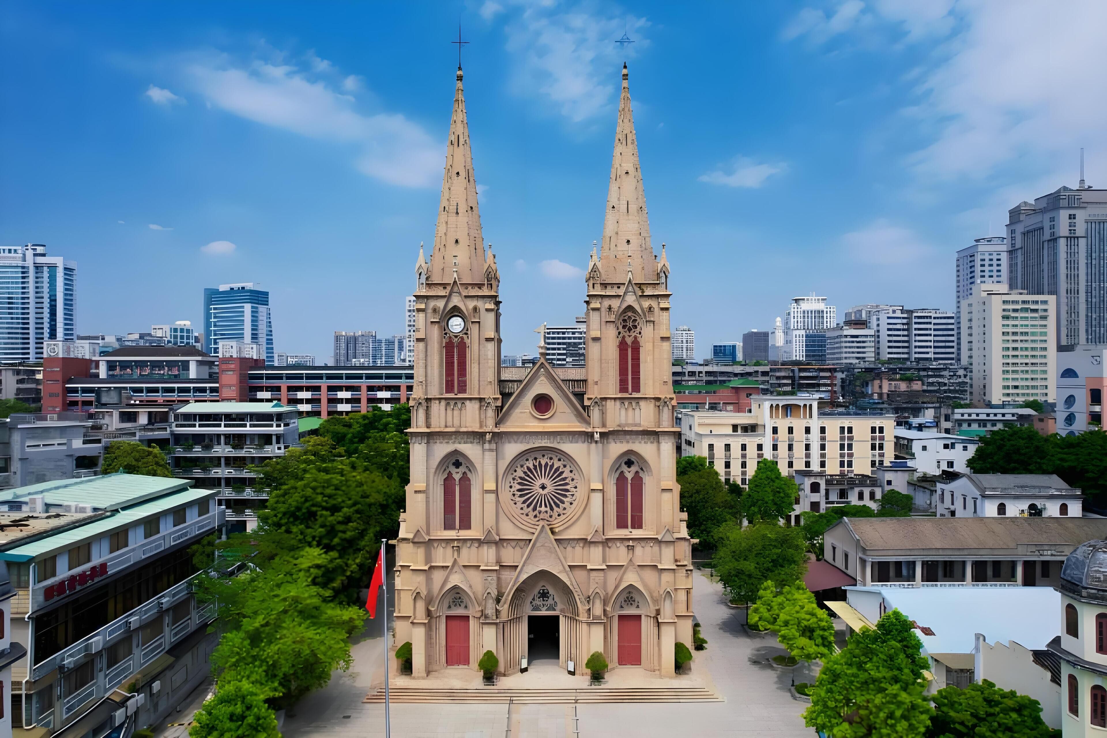 A large cathedral with two tall spires, surrounded by modern buildings and trees.