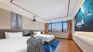 Una habitación de hotel moderna con dos camas, un ventanal con vistas a la ciudad, una pantalla de proyector y una alfombra azul.