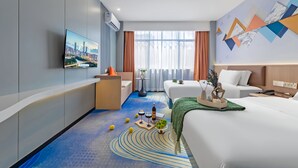Una habitación de hotel moderna con televisión mostrando un paisaje urbano, un sofá, una cama y una mesita con bebidas y fruta.