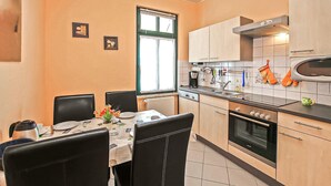A compact kitchen with a dining area, featuring a stove, oven, sink, and various kitchen utensils. - Gorgeous apartment in Waren (Müritz) (Waren (Müritz))