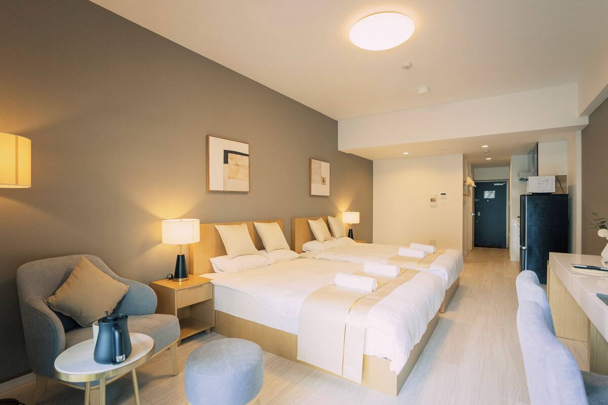 A hotel room with a large bed, a chair, a small table, and a desk.